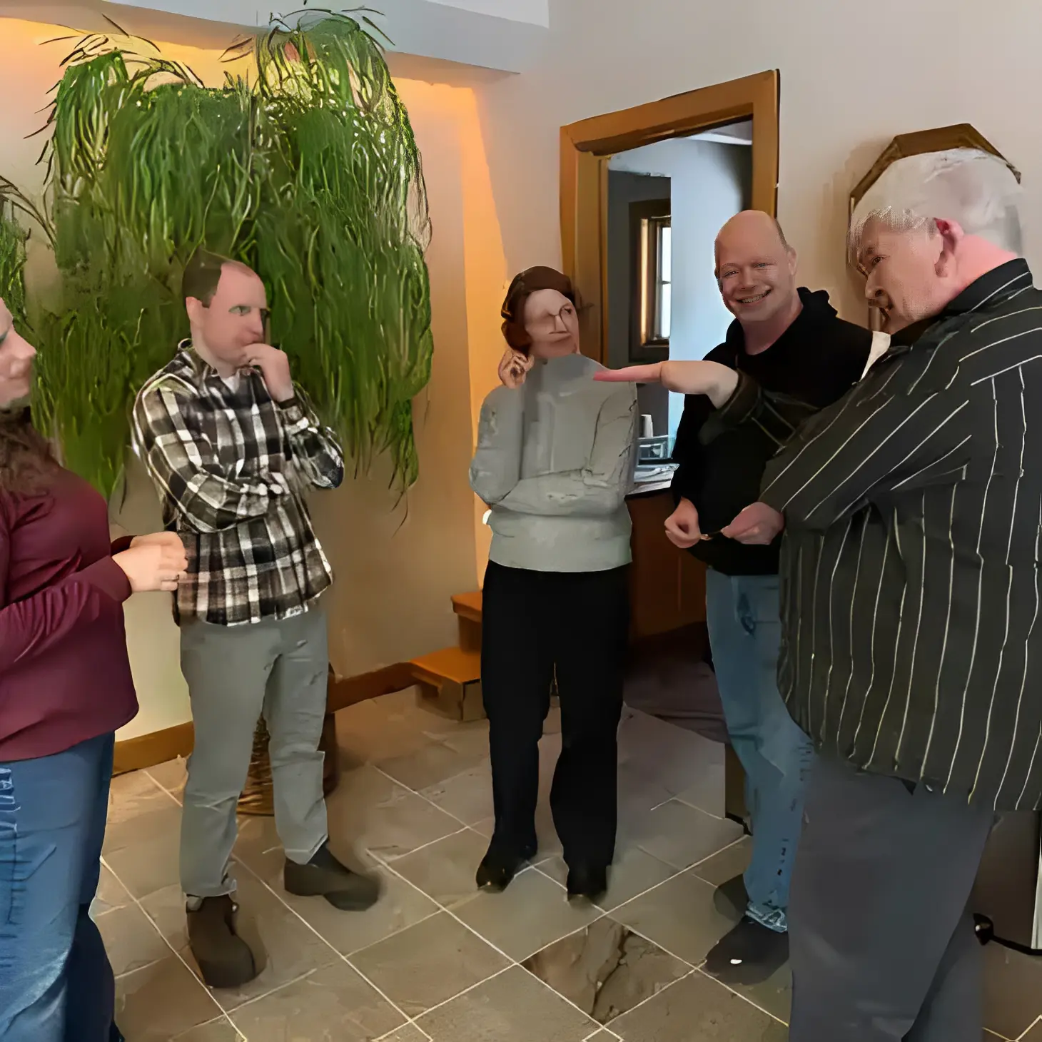 People engaged in conversation near a plant.