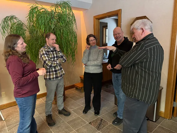 Five people engaged in a lively conversation indoors.