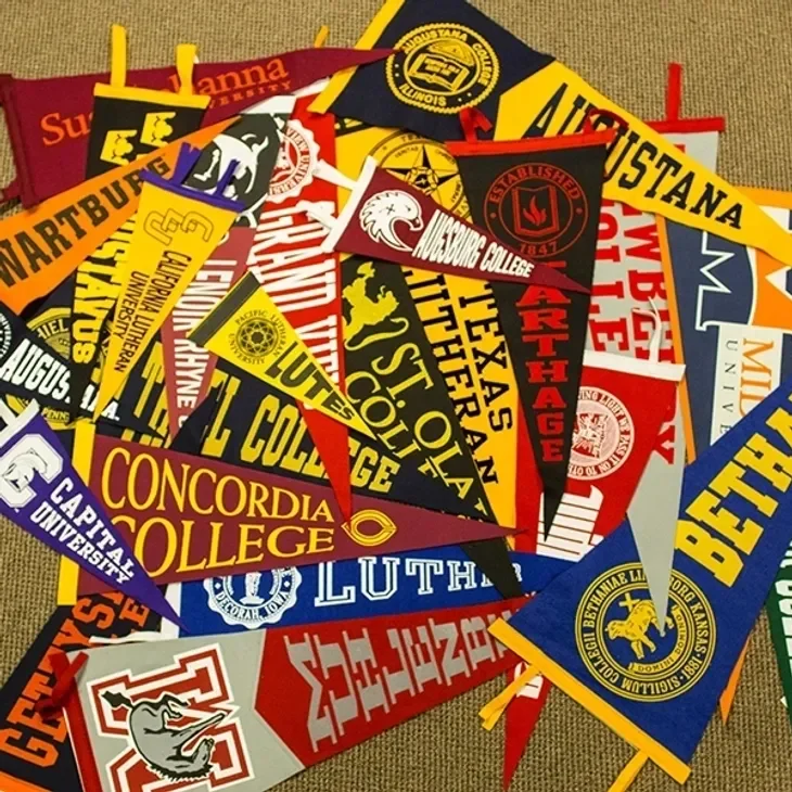 Assorted college flags overlapping each other.